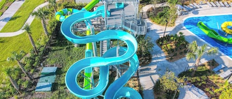 A water park with a large blue water slide, a pool, and a parking lot.