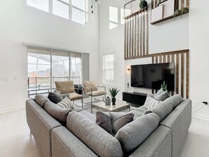 Una sala de estar moderna con un sofá modular, un televisor de pantalla plana y un ventanal con vistas al exterior.