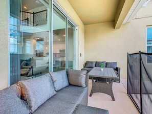 A modern outdoor living area with a sofa, a table, and a chair. - Theme Park Villa: Pool, Game Room, Family Getaway! (Davenport)