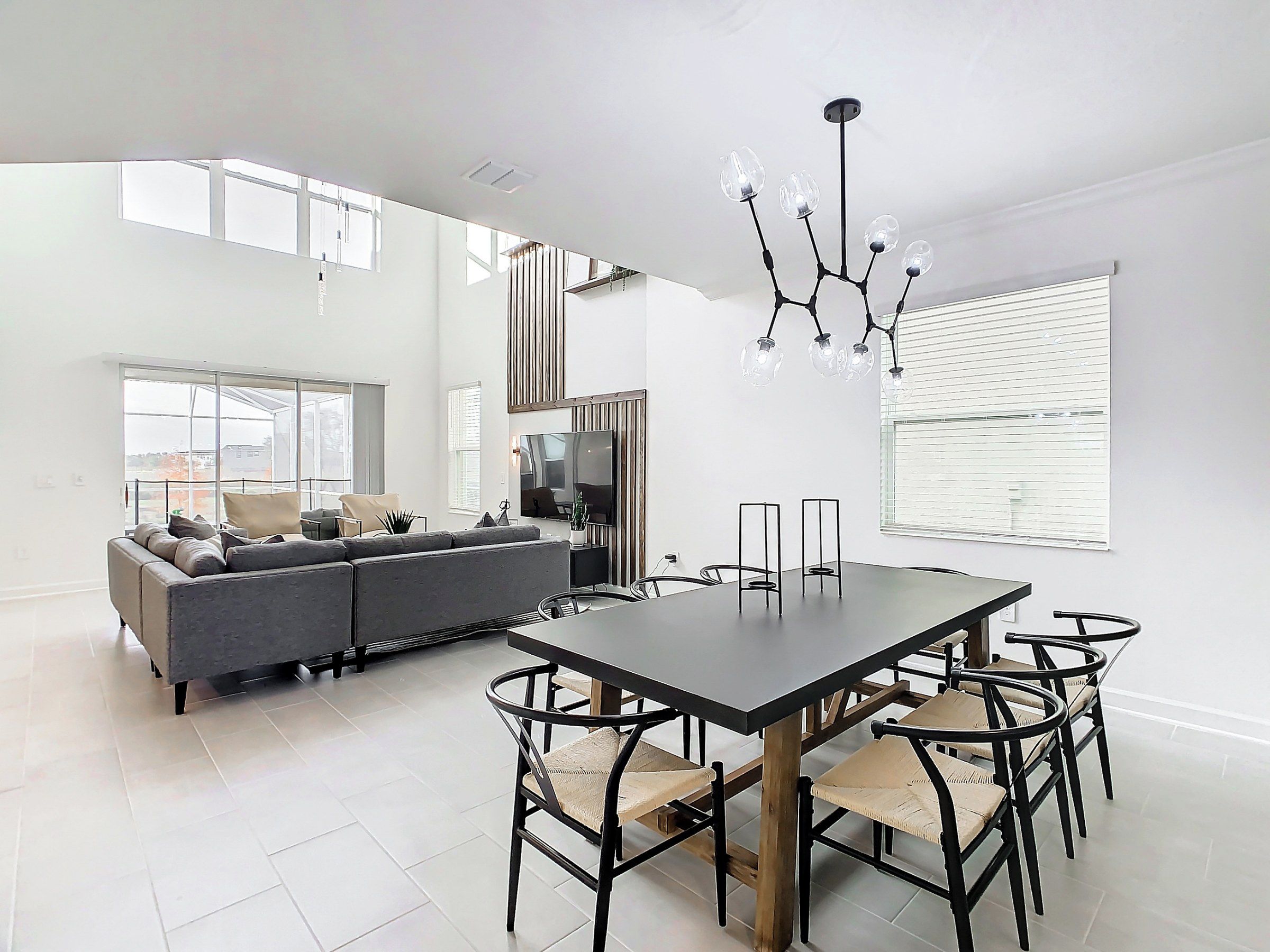 A modern living room with a sofa, dining table, chairs, and a TV.