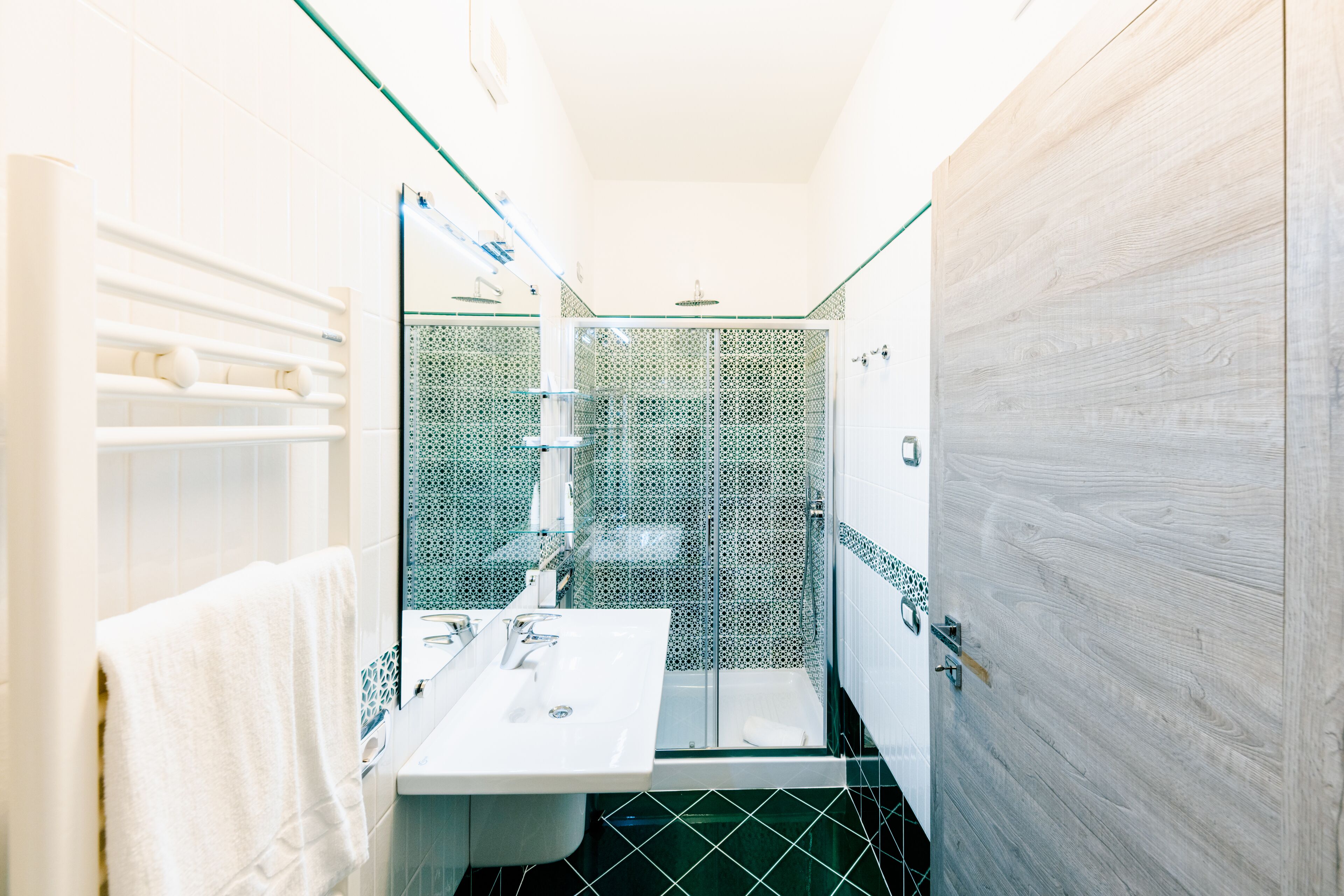 A modern bathroom with a glass shower enclosure, a white sink, and a wooden vanity.