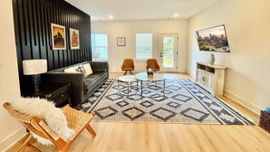 Un salon moderne avec un mur d’accent noir, deux fauteuils, un canapé, une table basse et un tapis à motifs.