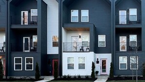 Un immeuble résidentiel à plusieurs étages, doté d’une façade symétrique, de balcons et d’une entrée centrale avec une porte rose.