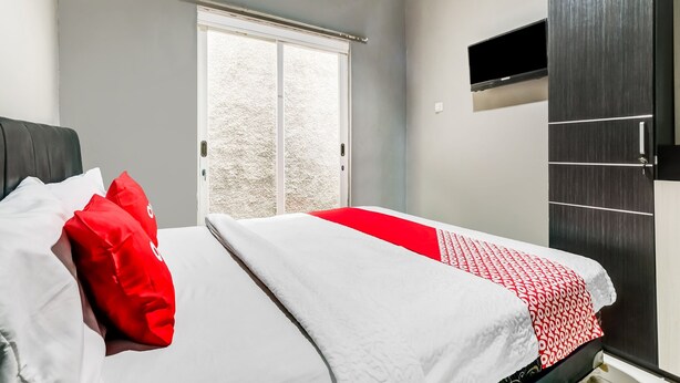 A bedroom with a bed, a wardrobe, and a sliding door to a balcony. - OYO Life 91239 Kost Rosandy House Yogyakarta (Ngaglik)