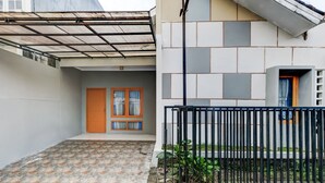 A modern building with a tiled courtyard, a wooden door, and a black metal fence. - OYO Life 91239 Kost Rosandy House Yogyakarta (Ngaglik)