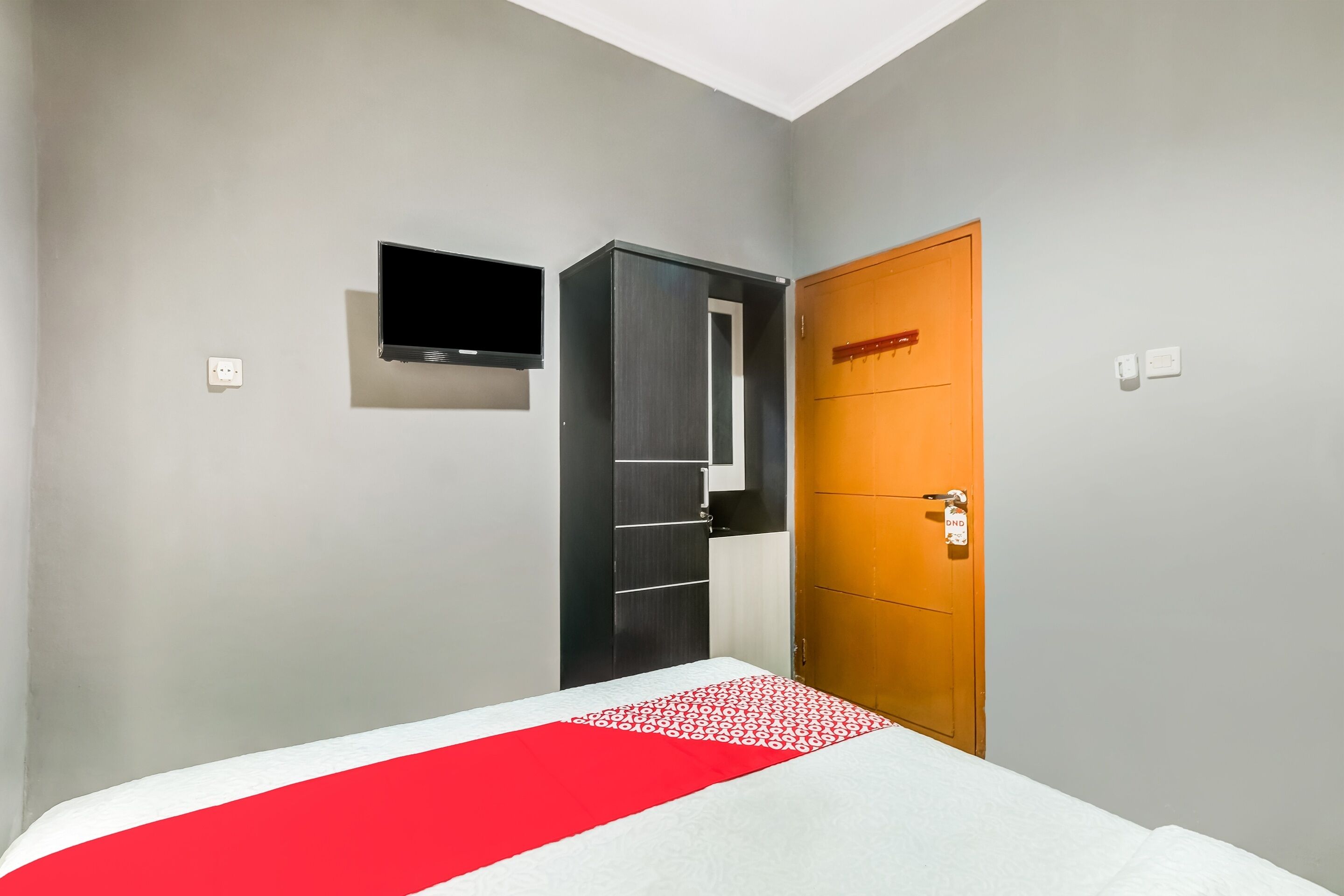 A bedroom with a bed, a wardrobe, a television, and a door.