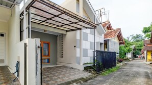 A residential building with a covered entrance, a tiled driveway, and a gated area. - OYO Life 91239 Kost Rosandy House Yogyakarta (Ngaglik)