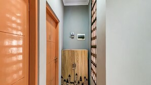 A hallway with a wooden wardrobe, a small air conditioning unit, and a window with blinds. - OYO Life 91239 Kost Rosandy House Yogyakarta (Ngaglik)