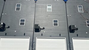 A row of three garage doors with a grey siding exterior. - Air-hockey garage game room, 3 queen bedrooms, sleeps 10 — 5 min to BNA, near Opry Mills (Nashvillle)
