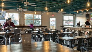 A restaurant with multiple tables and chairs, a bar area, and large windows allowing natural light. - 3-bed retreat with ping-pong game room, sleeps 10 — 5 min to BNA, near Opryland & the Opry (Nashvillle)