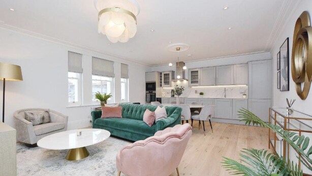 Un salon moderne avec un canapé vert, un fauteuil rose et une table basse blanche.