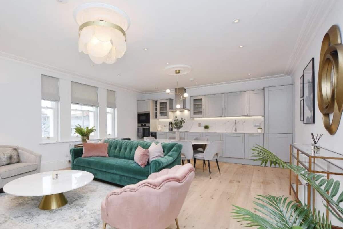 Een moderne woonkamer met een groene bank, een roze fauteuil en een witte salontafel.