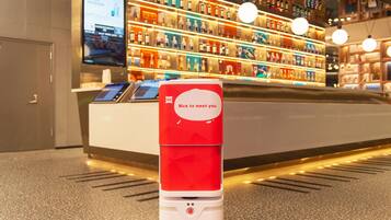 A red and white self-service kiosk in a hotel lobby with a digital screen and a message saying "Nice to meet you."