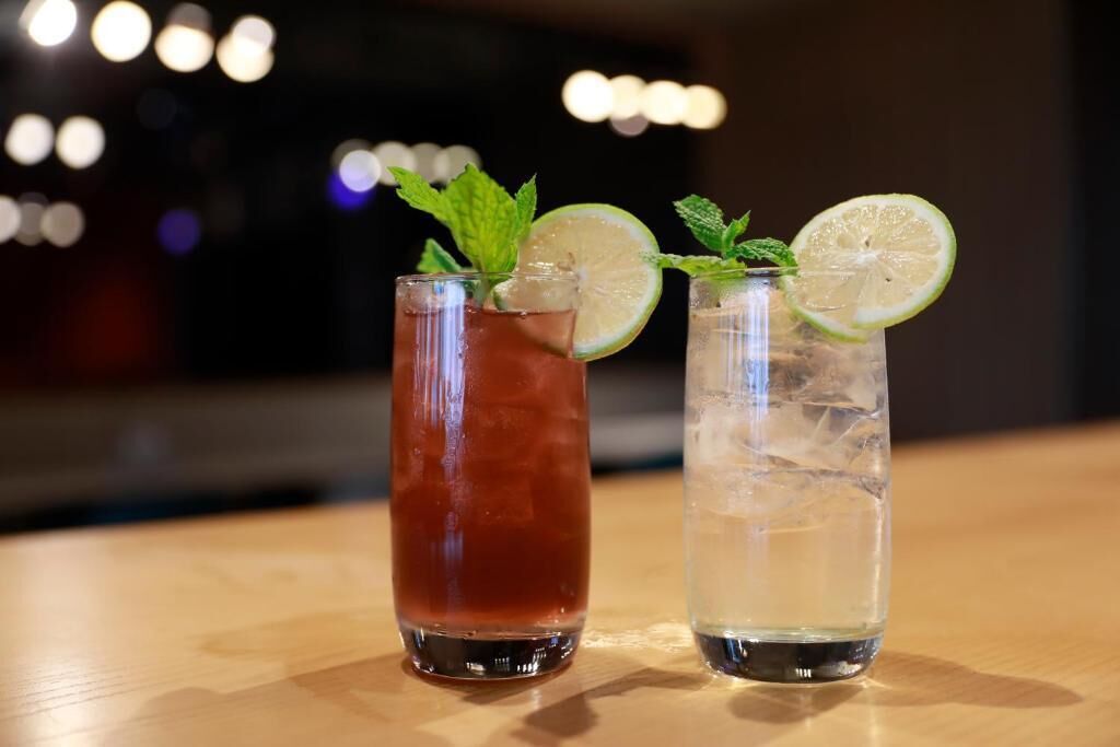Dos vasos de bebidas sobre una superficie de madera con luces desenfocadas al fondo.
