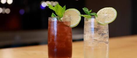 Dos vasos de bebidas sobre una superficie de madera con luces desenfocadas al fondo.