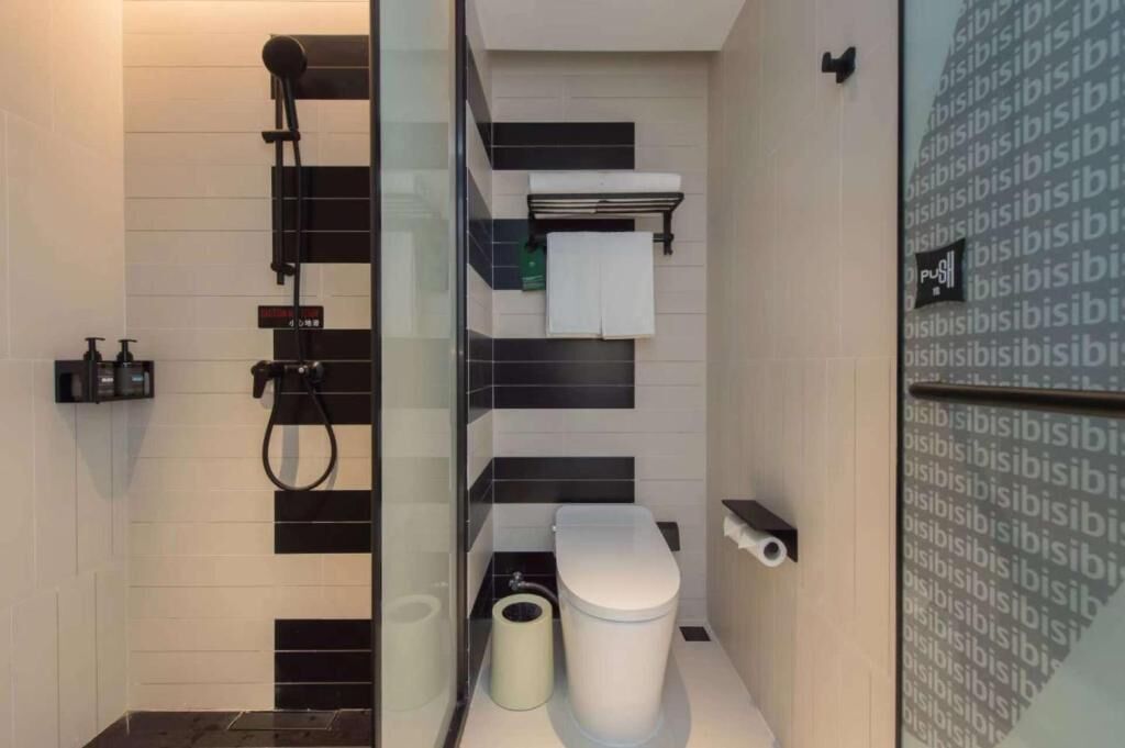 A modern bathroom with a glass partition, a toilet, a bidet, and a towel rack.