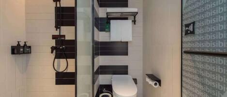A modern bathroom with a glass partition, a toilet, a bidet, and a towel rack.