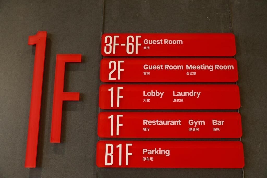 A hotel directory with red signs indicating various rooms and facilities, including guest rooms, meeting rooms, a lobby, laundry, a restaurant, gym, bar, and parking.