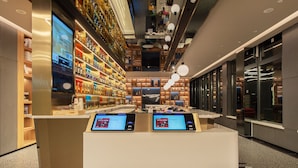 Un hall d'hôtel moderne doté d'un comptoir d'accueil, d'écrans numériques et de nombreux équipements, notamment un bar et des espaces de détente.
