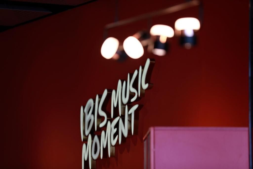 Et skilt med teksten 'IBIS MUSIC MOMENT' på en rød væg.
