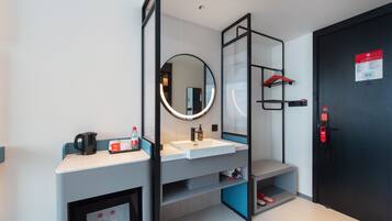 A modern bathroom with a white sink, a mirror, a shower area, and a door with a red emergency button.