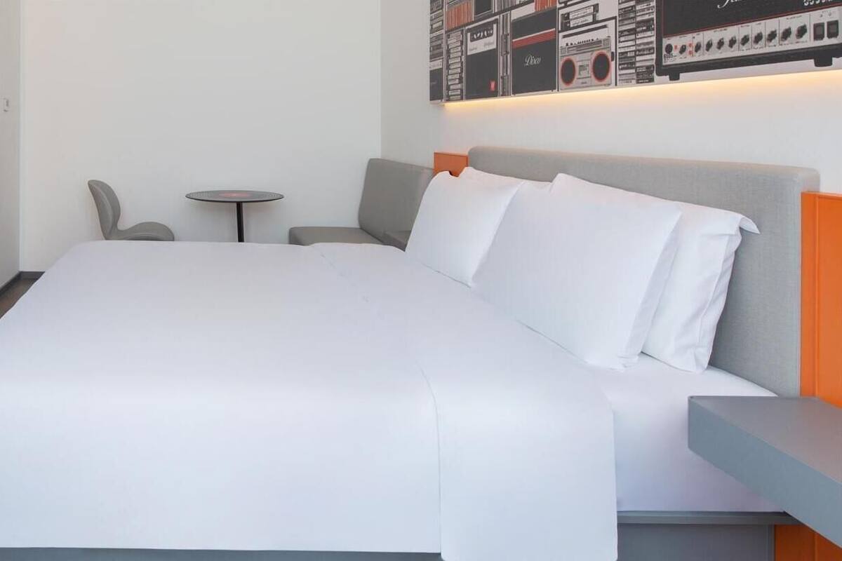 A modern hotel room with a large bed, a small round table, and a sofa.