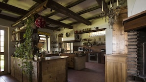 Una cocina rústica con vigas a la vista, una isla de ladrillo y una chimenea de piedra.