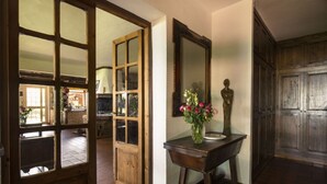 Una habitación con una puerta de madera, un espejo, un florero con flores y un armario.