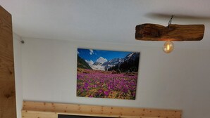 Una cama de madera con cabecera, una mesita de noche, un cuadro en la pared y una lámpara colgante.