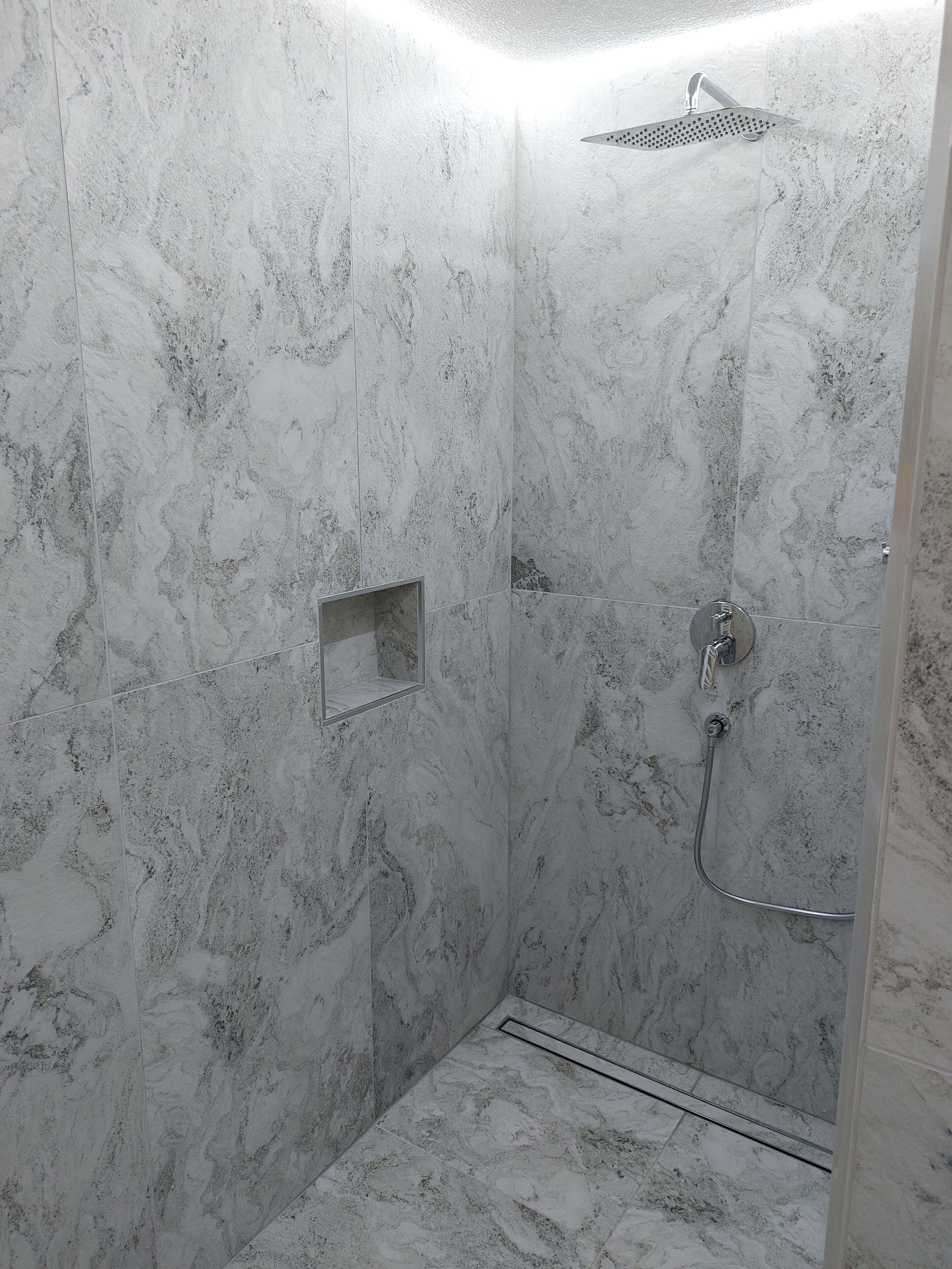 A shower with a handheld showerhead and a wall-mounted rain showerhead.