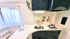 Une cuisine compacte avec un plan de travail blanc, des meubles de rangement sombres et une cuisinière intégrée.