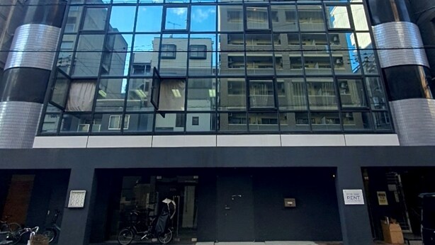 Un bâtiment moderne doté d’une façade en verre qui reflète le ciel et les bâtiments environnants.