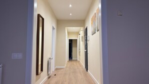 A hallway with a wooden floor, white walls, and a door at the end. - Anais Apartments by gaiarooms  (Barcelona)