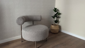 A corner of a room with a textured wall, a round chair with a unique backrest, and a potted plant. - Anais Apartments by gaiarooms  (Barcelona)