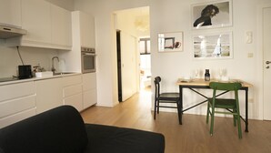Een moderne keuken met witte kasten, een inbouwoven en een eethoek met een tafel en stoelen.