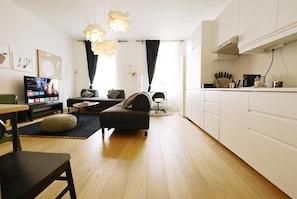 A modern living room with a sofa, ottoman, and a TV on a stand.