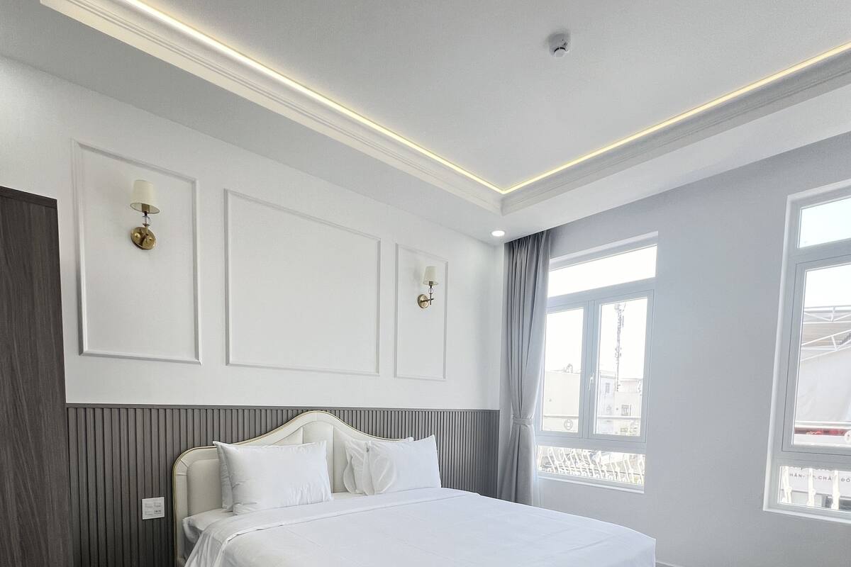 Habitación de hotel moderna con una cama grande, suelo de madera y vistas a la ciudad por la ventana.