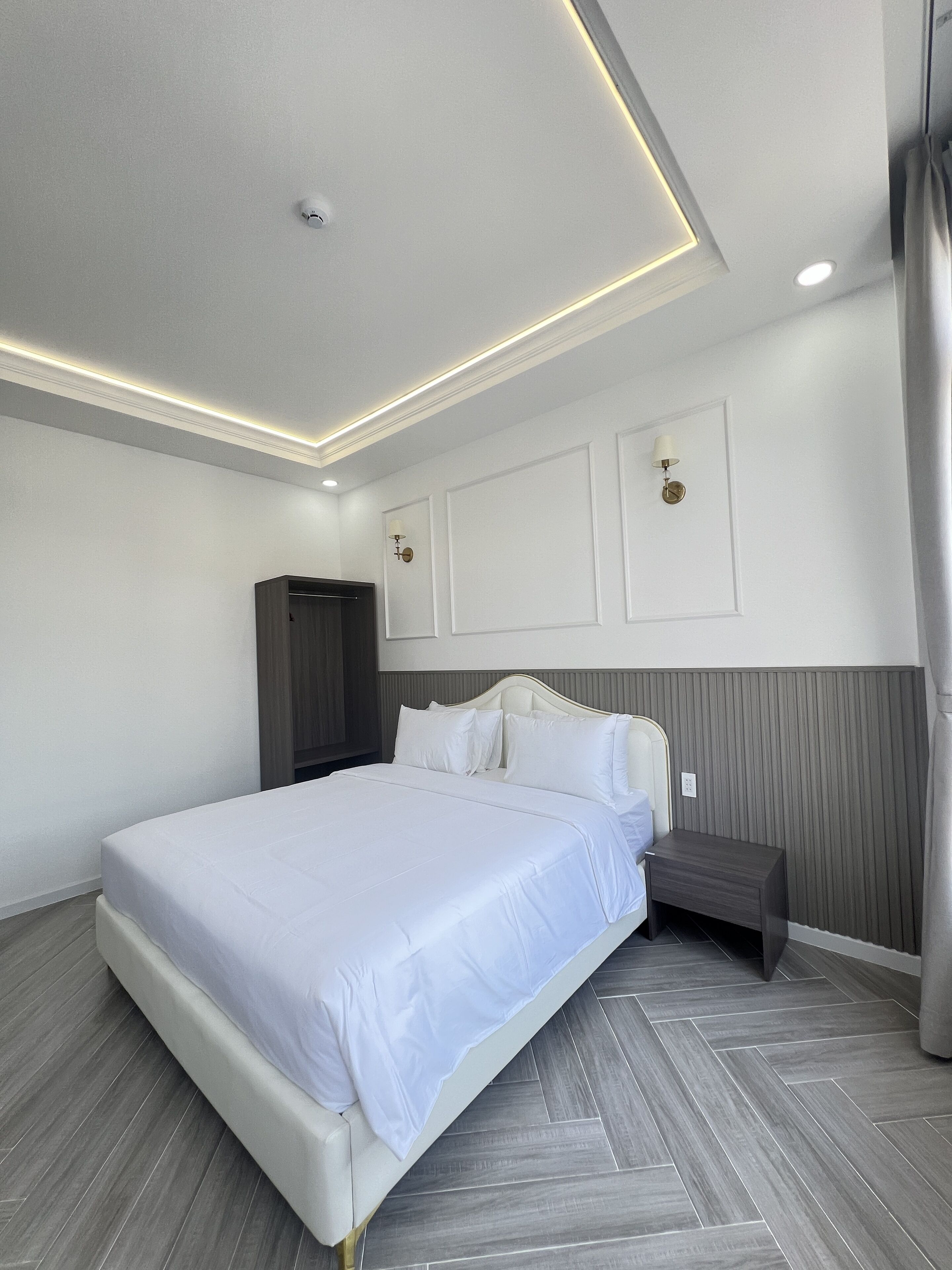 Une chambre à coucher moderne avec un grand lit, une table de chevet, une armoire et un luminaire au plafond.