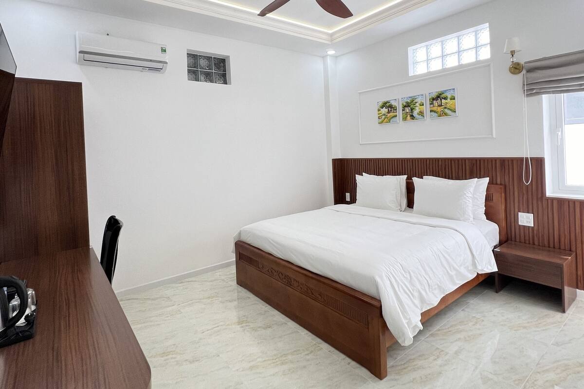 Un dormitorio moderno con una cama de madera, un ventilador de techo y piso de mármol.