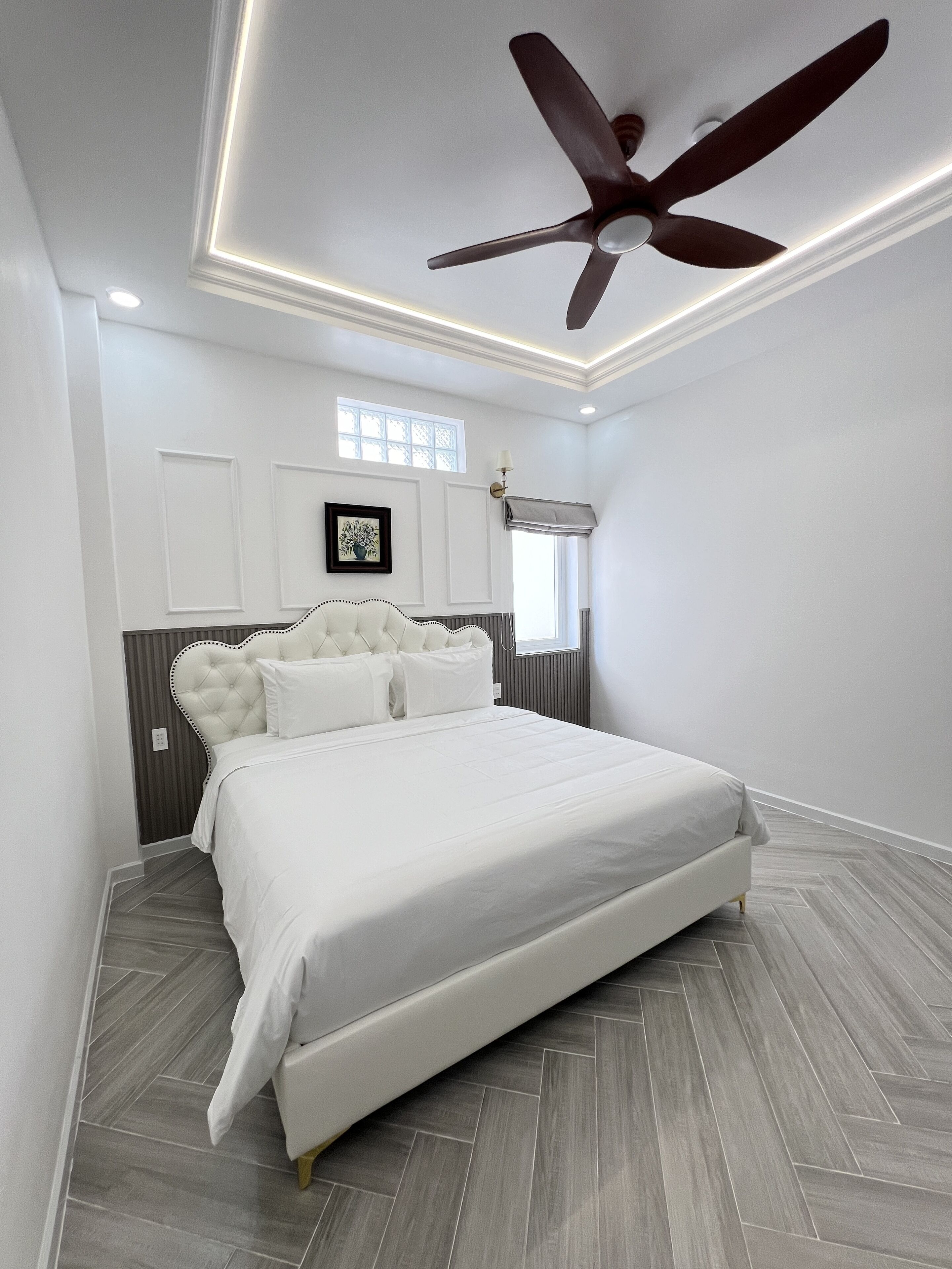 A modern bedroom with a large bed, a ceiling fan, and a window with a view.