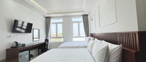 A hotel room with two beds, a desk with a chair, a television, and a window with curtains.