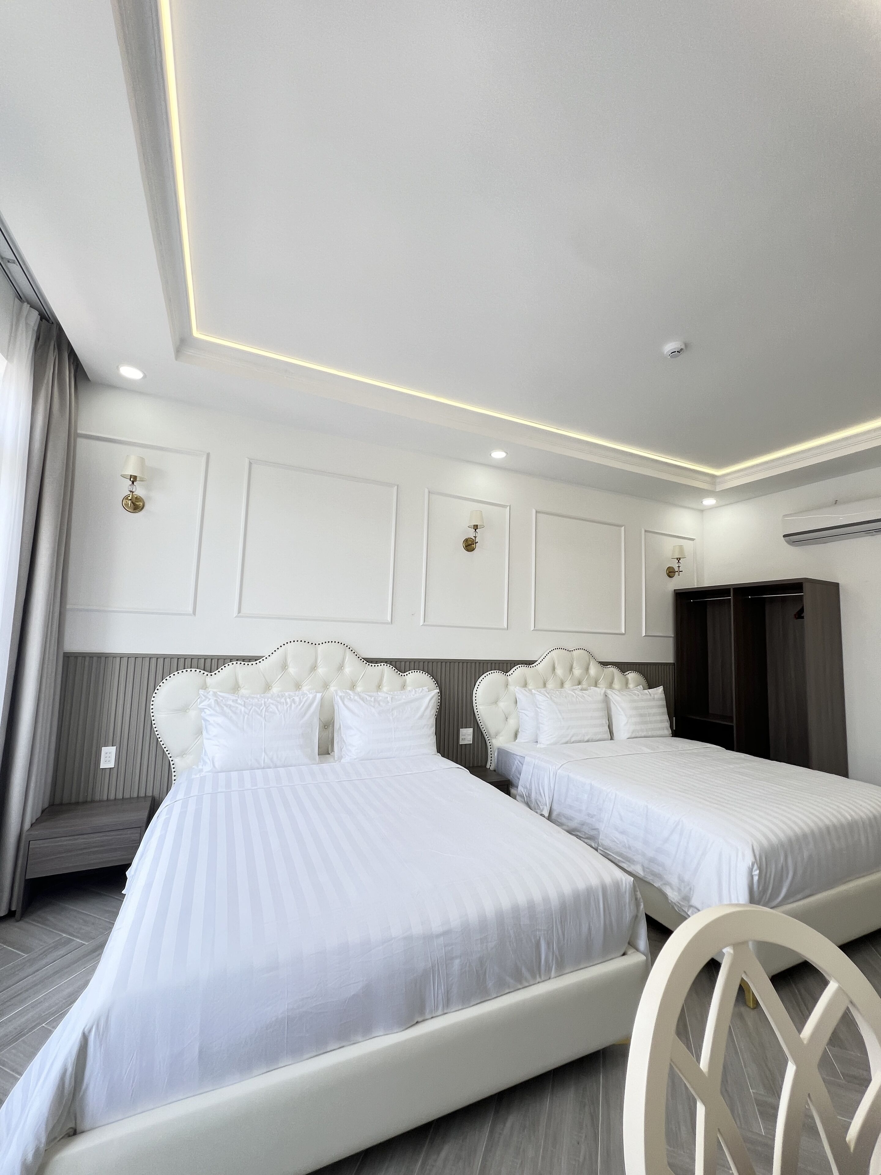 A hotel room with two beds, a seating area, and a wardrobe.