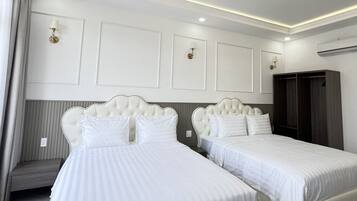 A hotel room with two beds, a seating area, and a wardrobe.