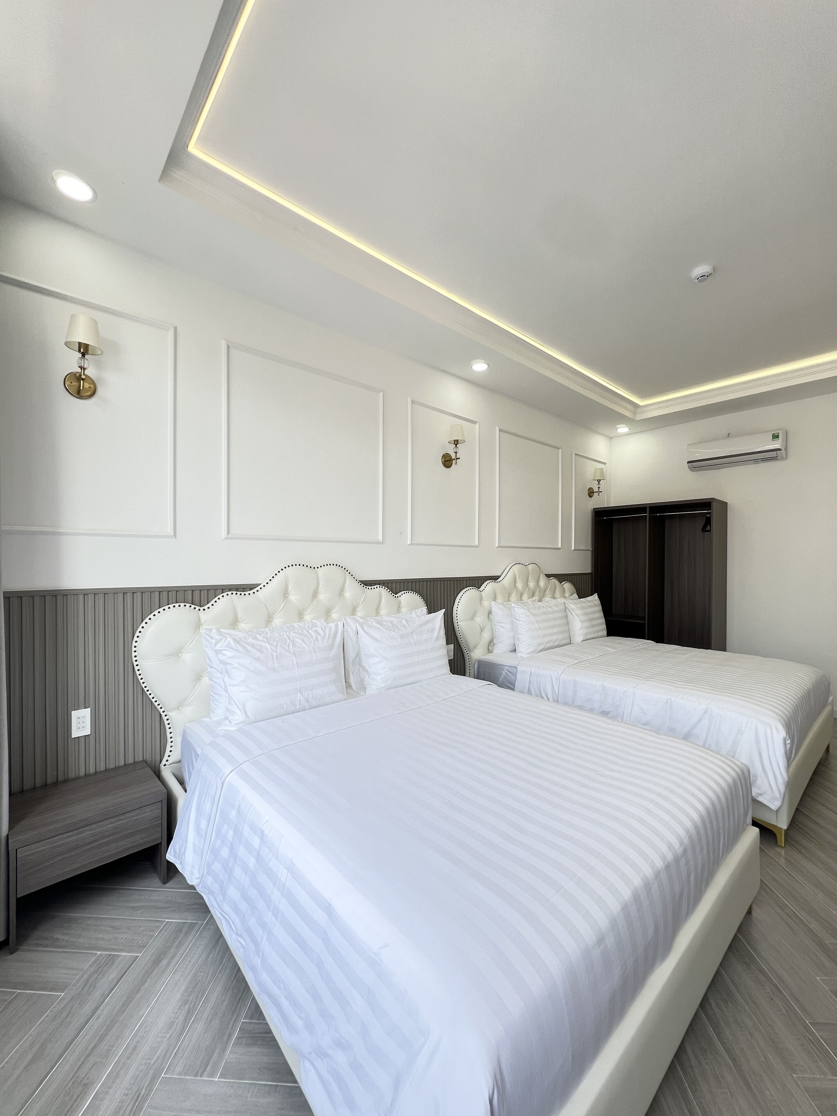A modern bedroom with two beds, a wardrobe, and an air conditioning unit.