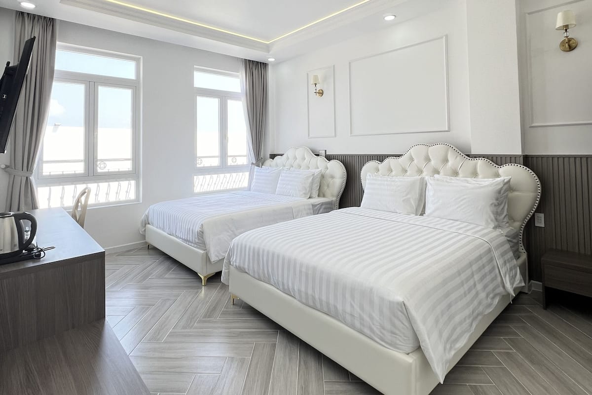 Una habitación de hotel moderna con dos camas, un escritorio y un ventanal grande.