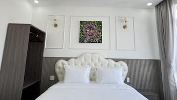 A hotel room with a large bed, a wardrobe, a ceiling light, and a wall-mounted artwork.