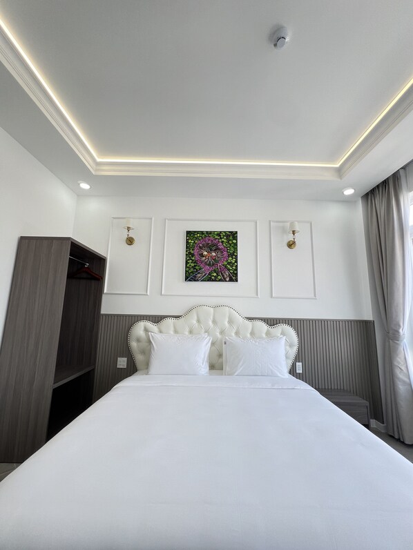 A hotel room with a large bed, a wardrobe, a ceiling light, and a wall-mounted artwork.