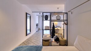 Una habitación de hotel con cama, zona de estar con mesa, televisor y armario.