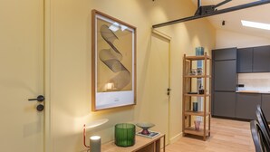 A modern kitchen with grey cabinets, a wooden shelf unit, and a framed artwork on the wall.