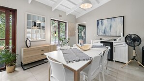 A modern kitchen with white cabinetry, a dining table with chairs, a large abstract painting, and a fan. - San Lameer Villa 2412 (Southbroom)